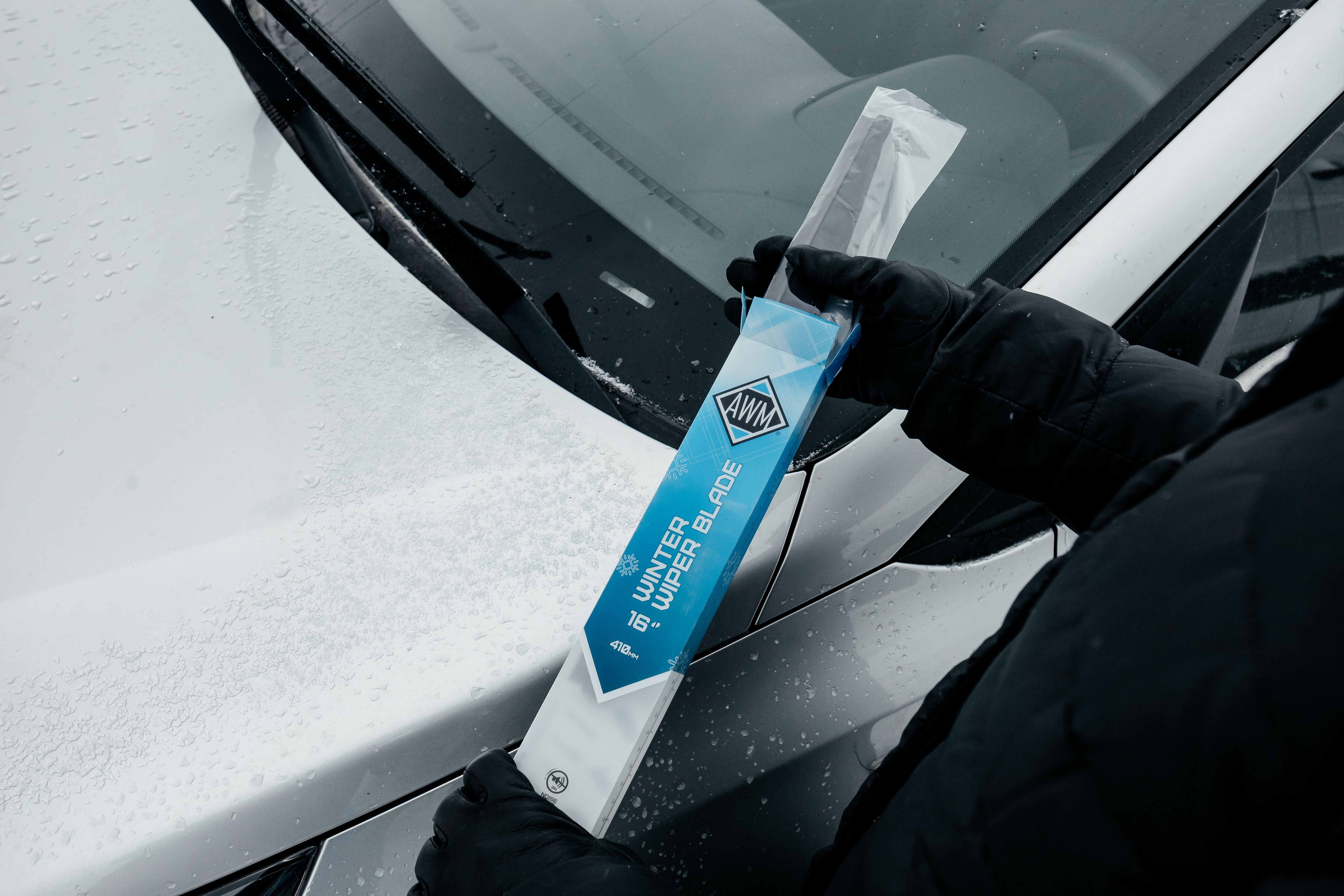 Щетка стеклоочестителя на фоне машины и снега
